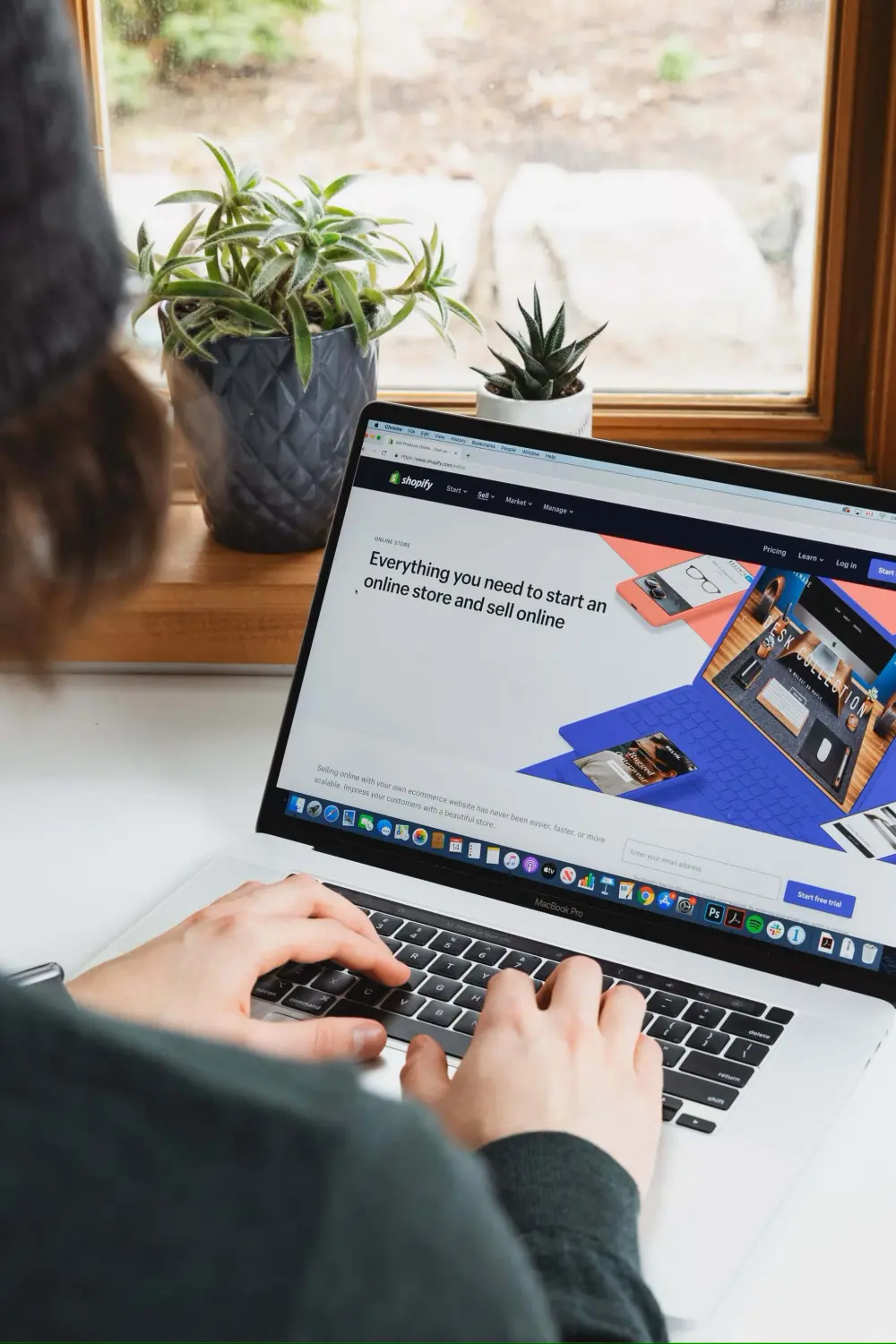 Utilisatrice de la plateforme de vente en ligne Shopify devant une fenêtre
